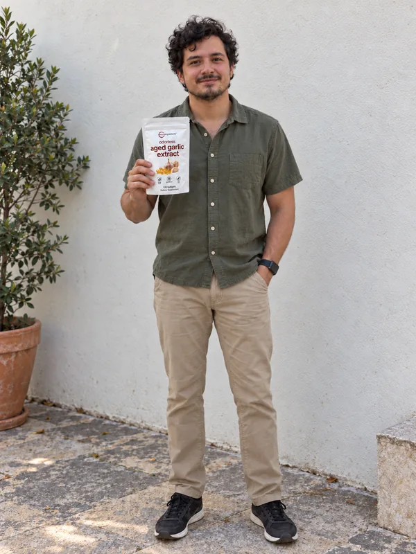 Escena ficticia con IA: Pablo de cuerpo entero, mirando a cámara con Aged Garlic Extract.